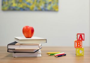 apple on stack of books next to ABC blocks